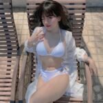 Ảnh Bảo Hân Helia mặc bikini trắng ngồi ghế dài tắm nắng