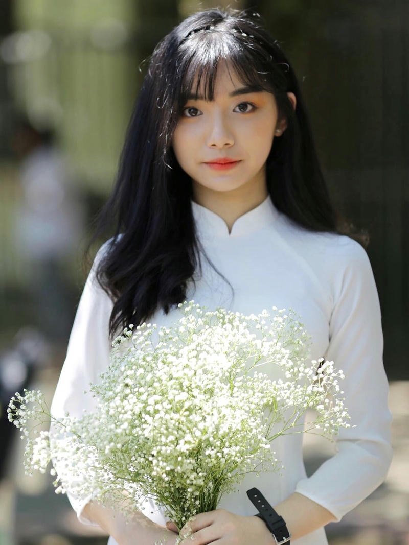 Ảnh Quỳnh Trương Tiktok mặc áo dài trắng cầm hoa trắng