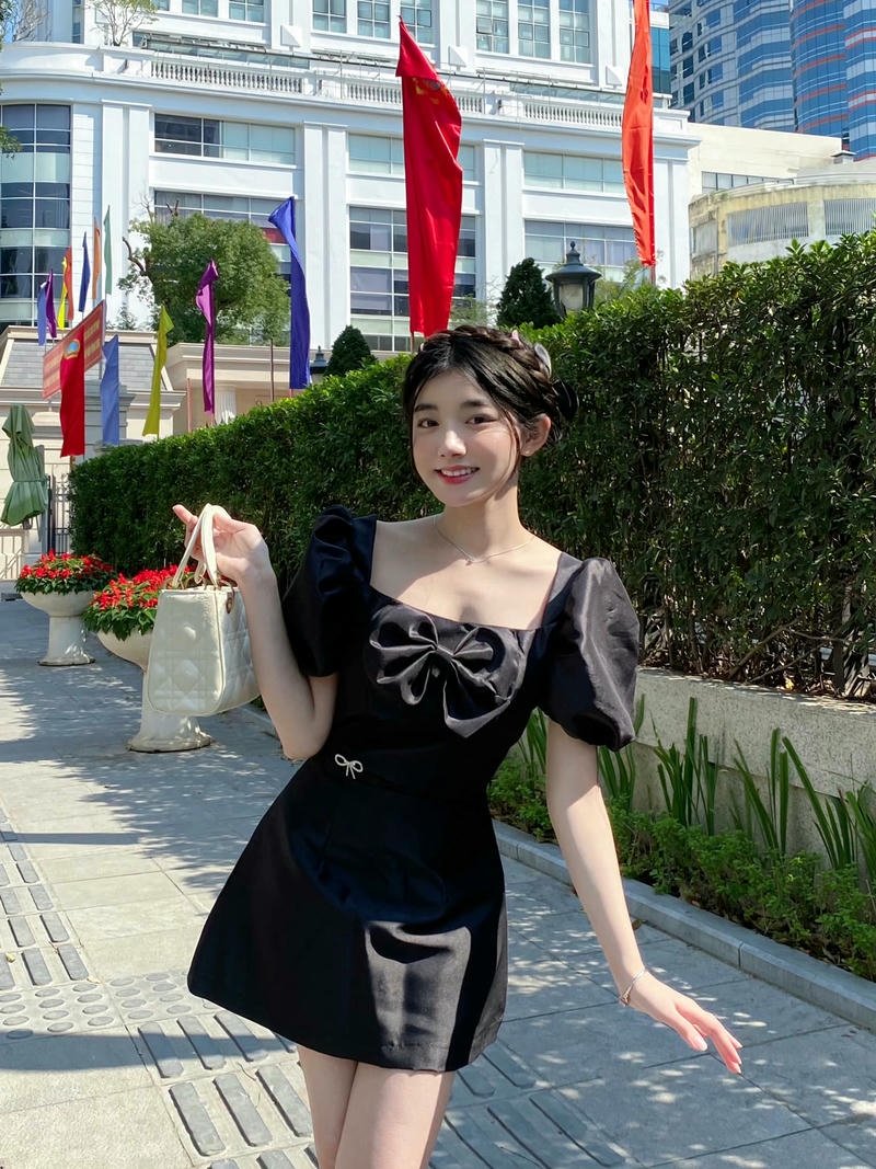 Ảnh Quỳnh Trương Tiktok mặc váy đen đứng cạnh hàng rào