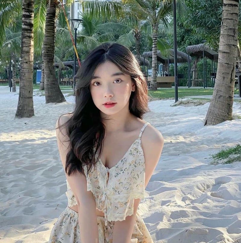 Ảnh Quỳnh Trương Tiktok mặc váy hoa ngồi dưới tán cây xanh