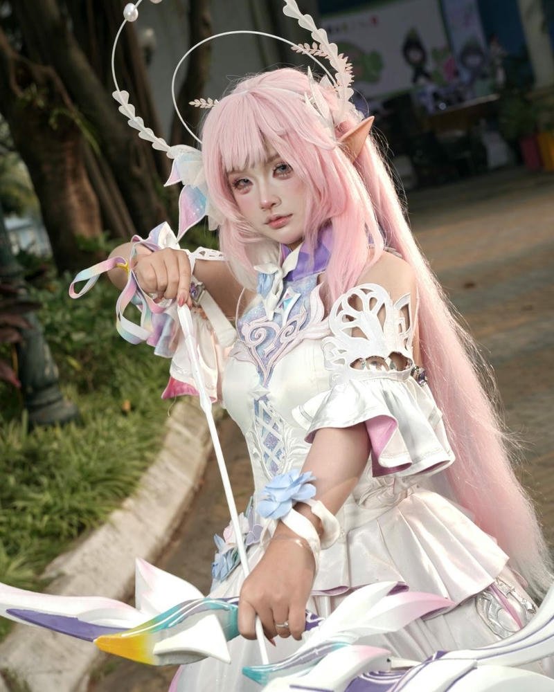 Ảnh cosplay anime nữ sinh tóc hồng cầm hoa đứng ngoài trời
