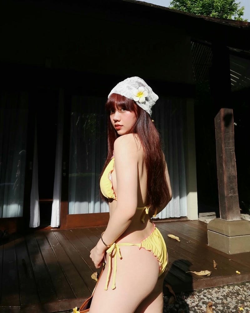 Bảo Hân Helia bikini vàng rực rỡ đứng dưới bóng râm mát