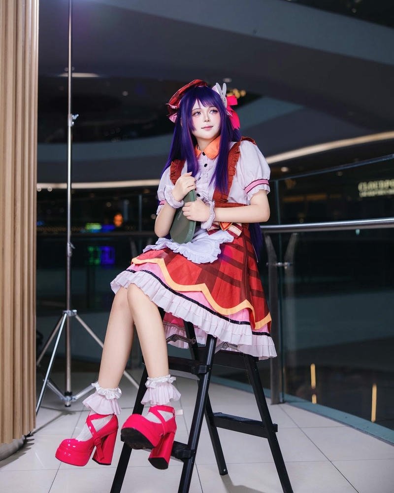 Cosplayer nữ tóc tím ngồi ghế cao tạo dáng chân dài