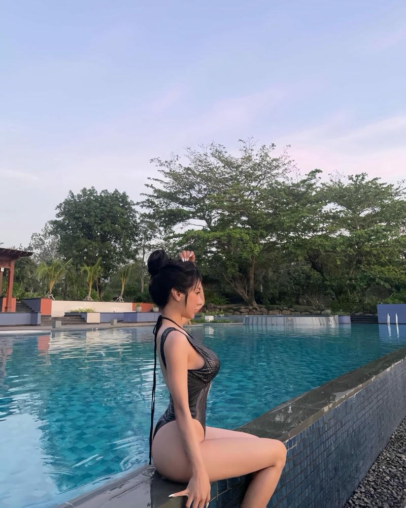 Phạm Hồng Nhung mặc bikini đen ngồi bên cạnh hồ bơi