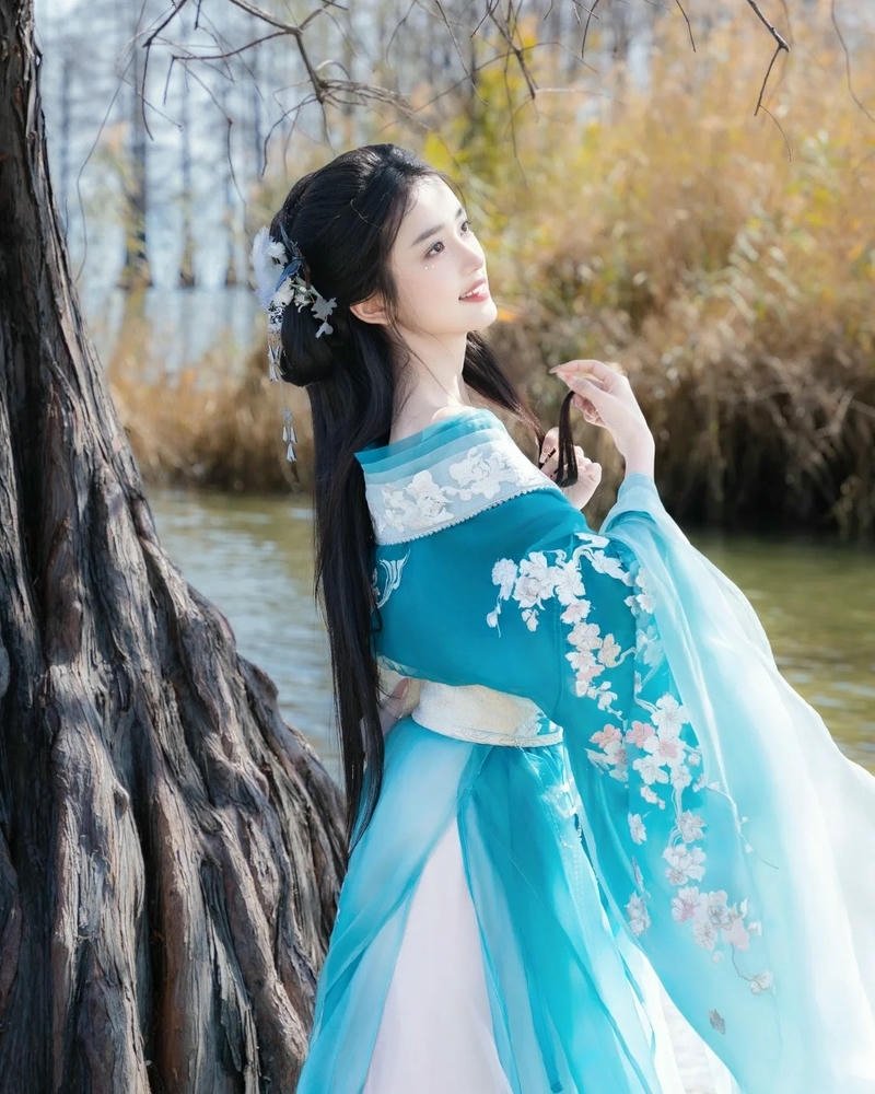 Tiên nữ cổ trang váy xanh đứng tựa gốc cây lãng mạn