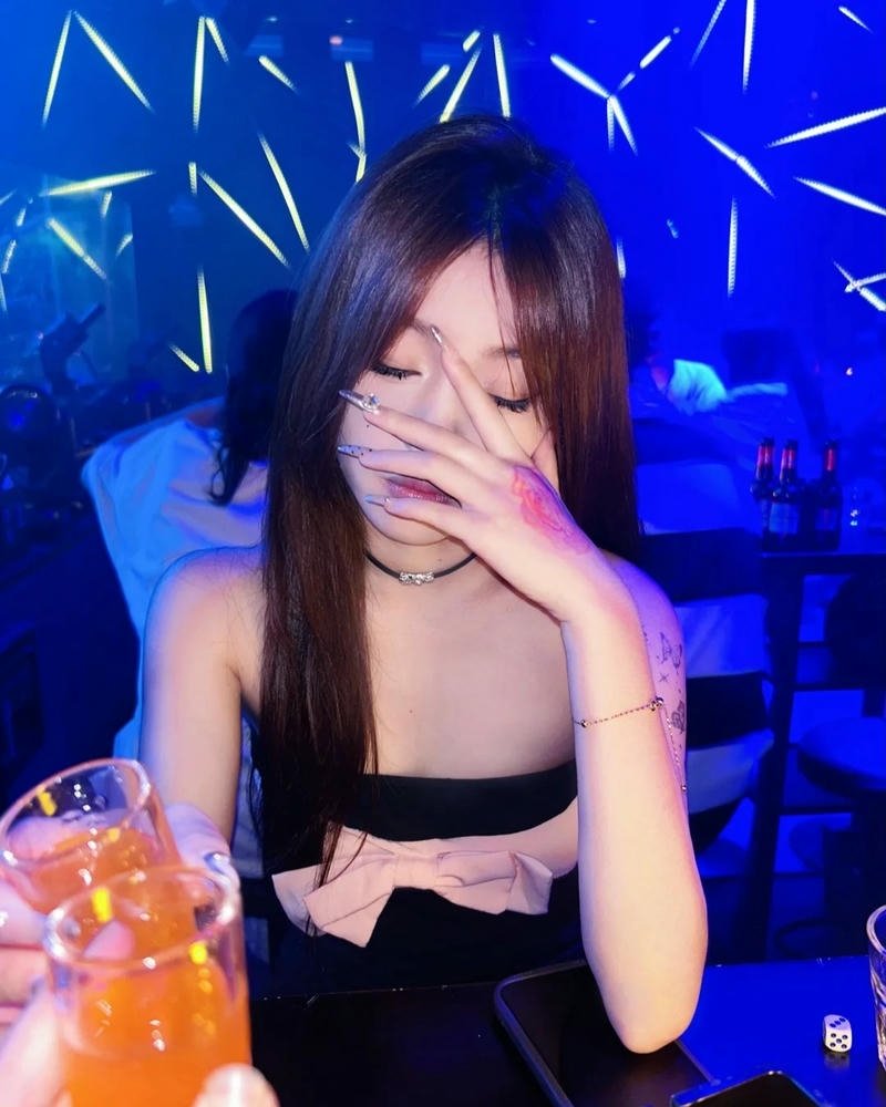 Ảnh gái đi bar che miệng cười dưới ánh đèn xanh