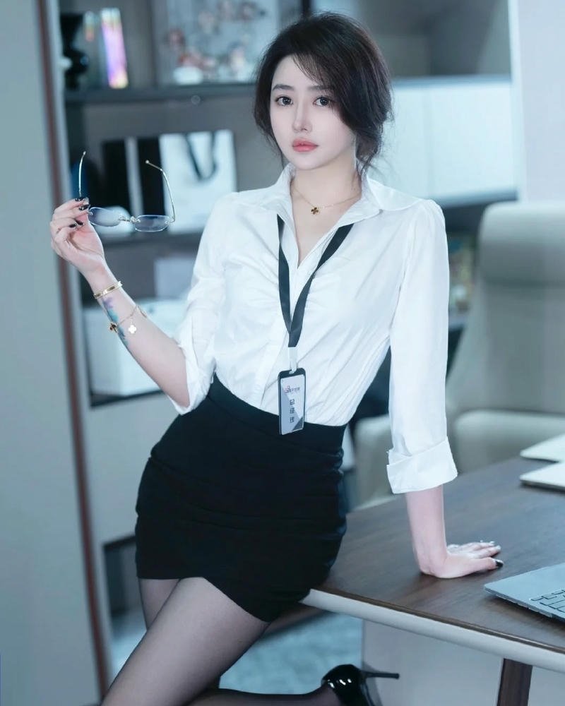 Ảnh gái văn phòng mặc áo trắng váy đen ngồi trên bàn