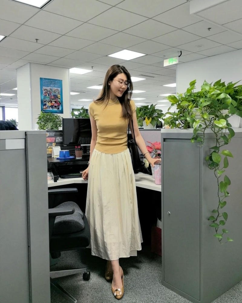 Ảnh gái văn phòng mặc váy vàng đứng giữa không gian làm việc