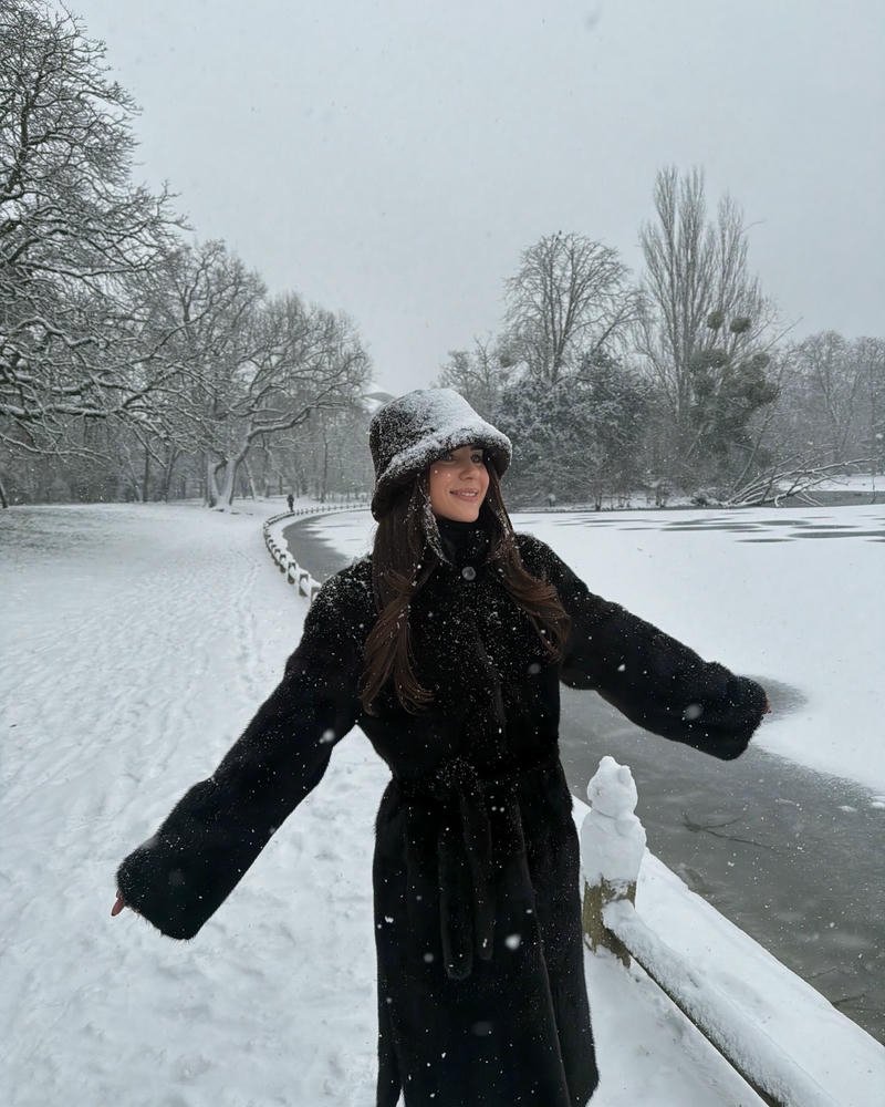 Gái tây mặc áo khoác đen đứng giữa trời tuyết