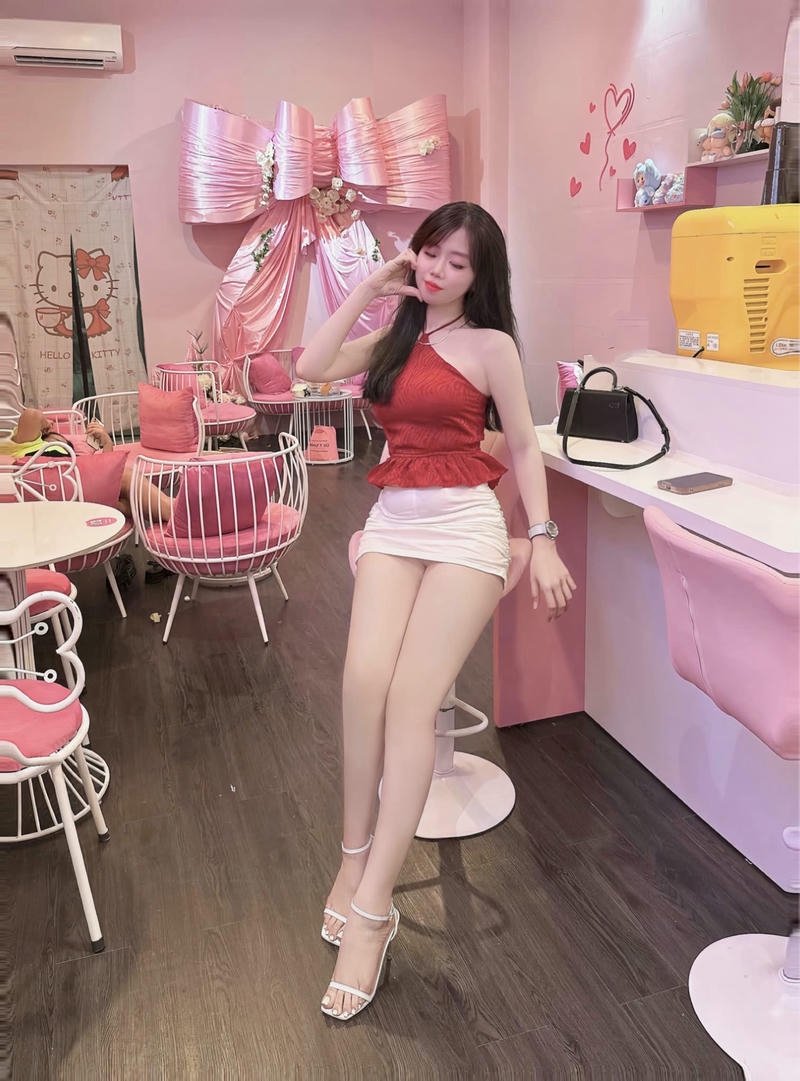 Gái xinh mặc váy ngắn màu hồng ngồi trong quán cafe