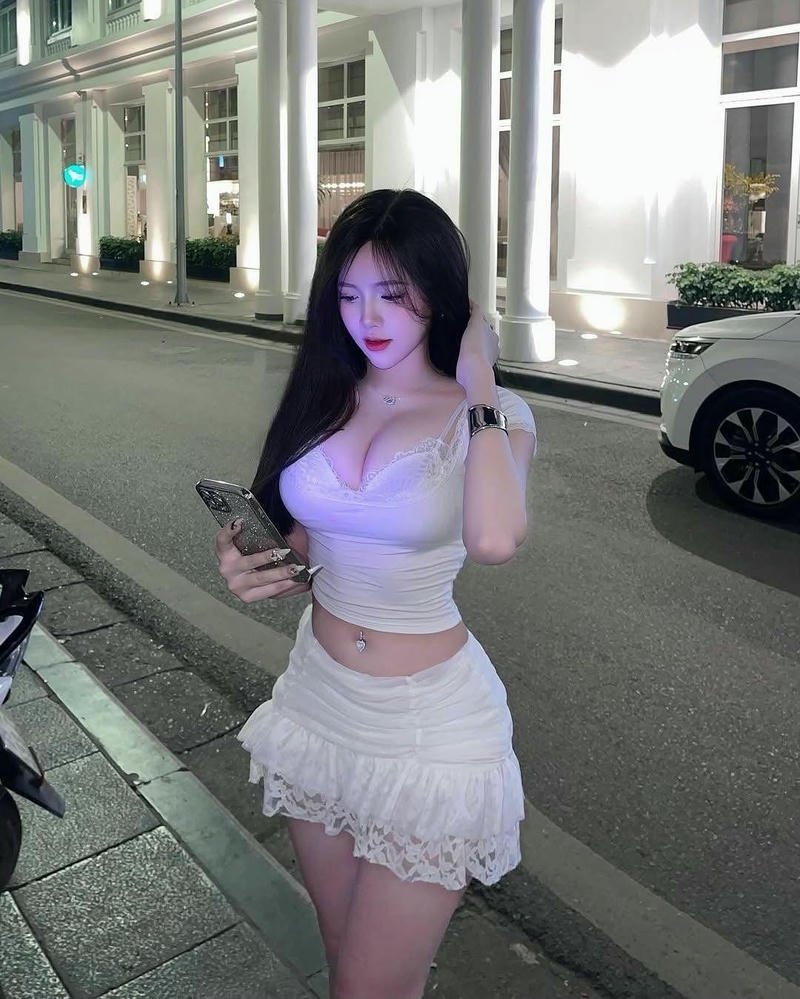 Gái xinh mặc váy ngắn màu trắng đi dạo trên phố