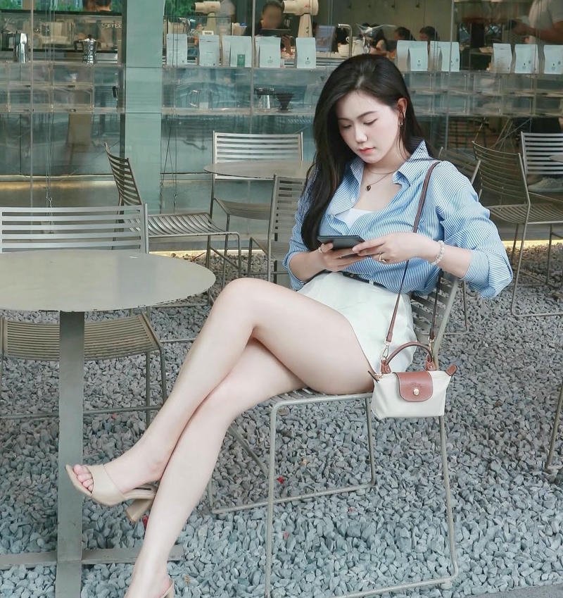 Gái xinh mặc váy ngắn ngồi vắt chân trên ghế đá