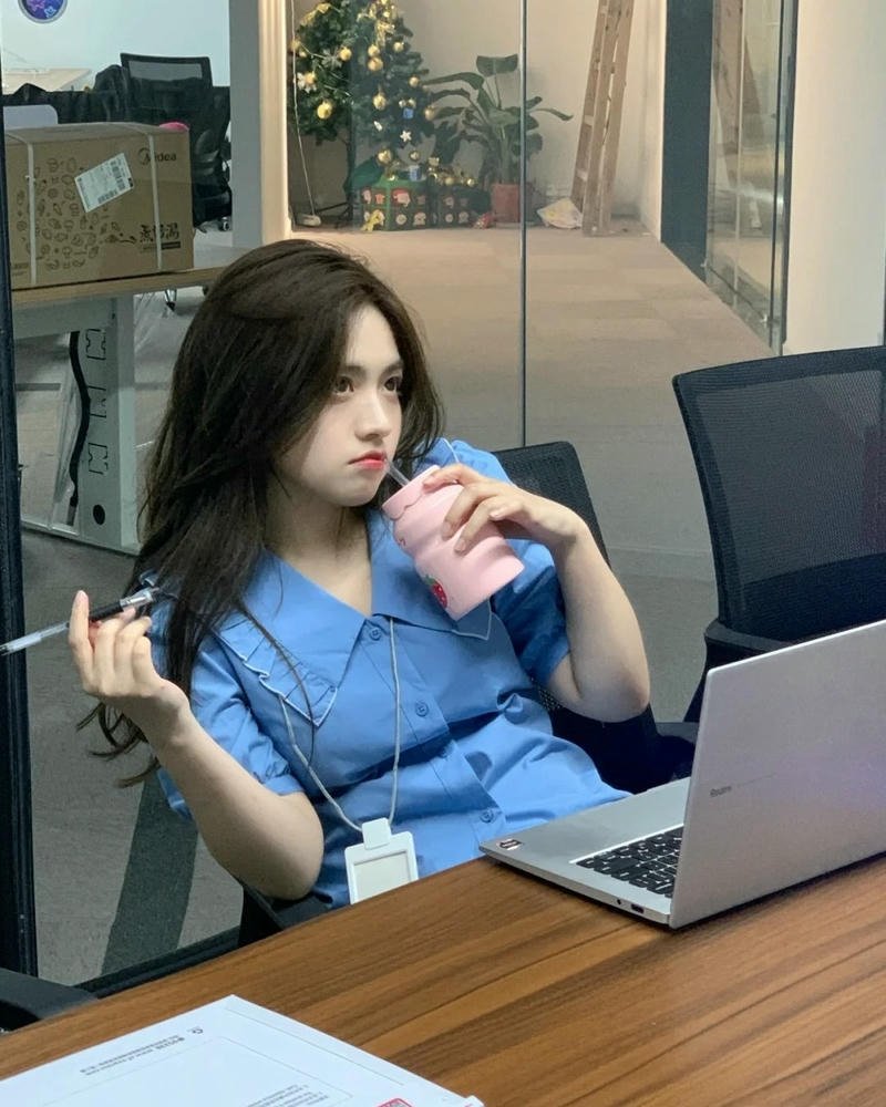 Girl xinh văn phòng mặc áo xanh ngồi bàn làm việc