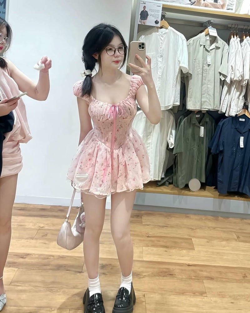 Hot girl mặc váy hồng đứng trong shop quần áo