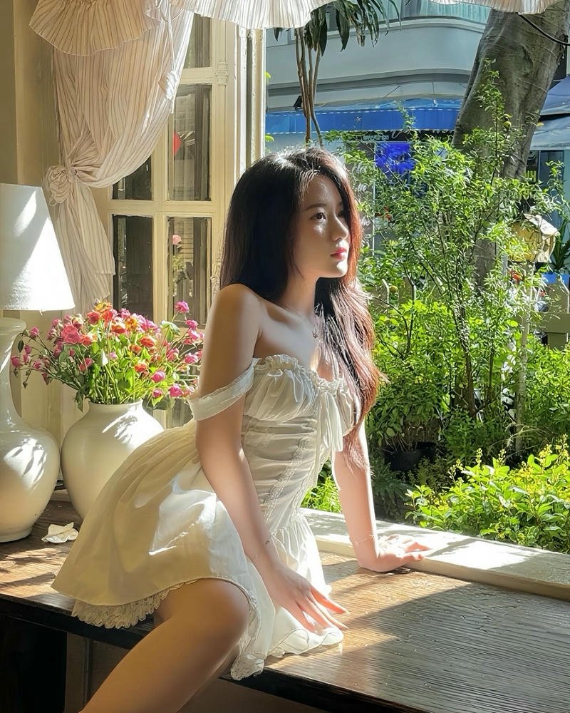 Người mẫu ảnh đẹp váy trắng ngồi ghế vườn xinh